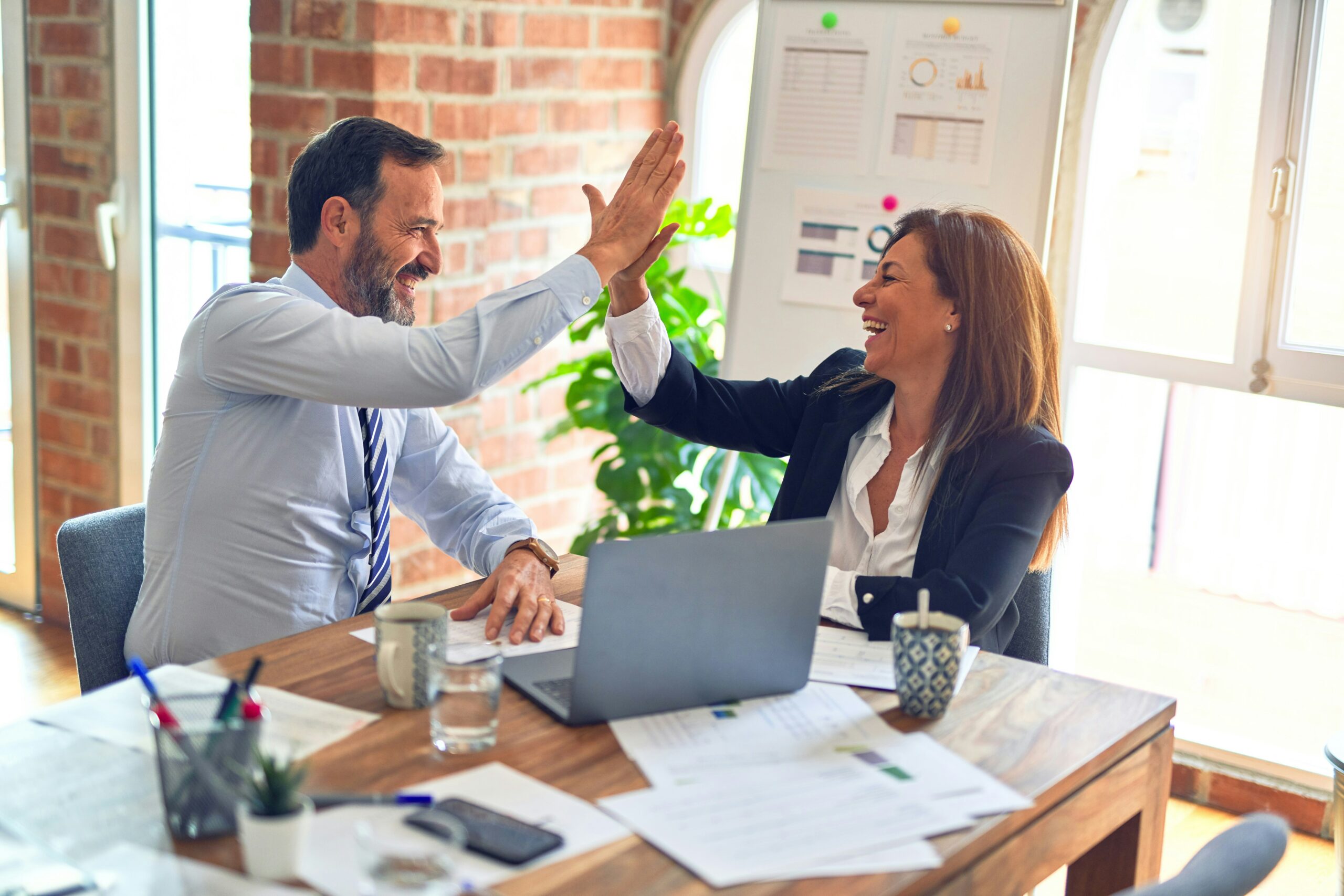 Two coworkers high-fiving each other in an office